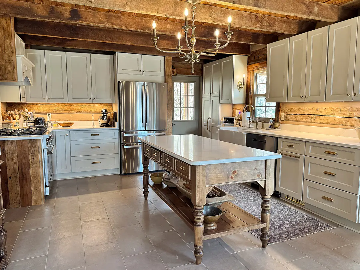 Pale sage green cabinetry in a log cabin with brown wood island